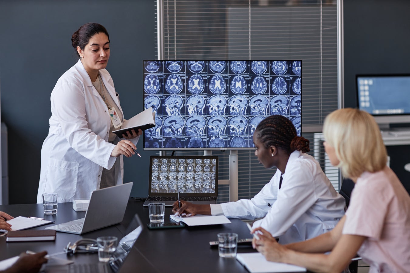 Female neurologist giving report on patient treatment showing brain MRI.