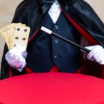 Illusionist holding magic wand and playing card.