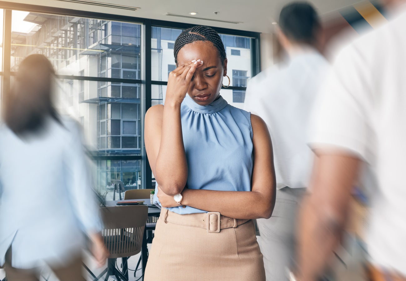 Office workplace featuring a stressed woman employee having a headache.